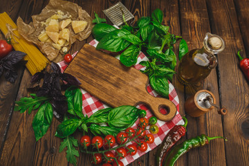 Pasta background. Dry spaghetti with cheese, vegetables and herbs on a wooden table.