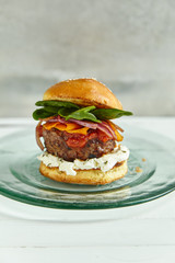 Burgers with grilled beef patties, cream cheese and spinach on classical bun. White wooden background