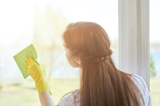 Woman cleaning a window. Person wiping glass with rag. Tips for housewives.