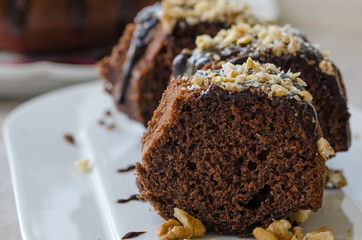 Chocolate cake, sliced, covered with coconut and walnut.