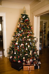 Christmas tree filled with vintage ornaments decorates the corner of a living room with wood floors