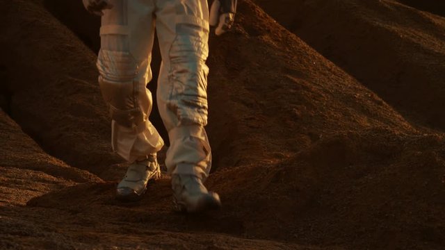 Astronaut Wearing Space Suit Walks On the Rocky Terrain of the Red Planet/ Mars. Focusing on Legs. Rocks and Sand Planet. Shot on RED EPIC-W 8K Helium Cinema Camera.