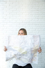Young blonde women peaks over the top of a map