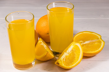 Fototapeta na wymiar Glass of orange juice and fresh oranges on white wooden table