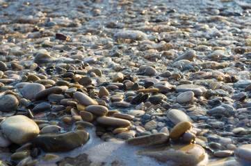 Obraz premium pebble stones on the sea beach, the rolling waves of the sea with foam