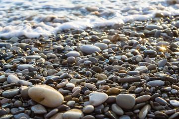 pebble stones on the sea beach, the rolling waves of the sea with foam