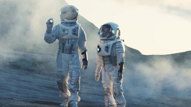 Two Astronauts Explore Rocky Alien Planet in the Day Time. Near Future and Technological Advance Brings Space Exploration, Travel, Colonization Concept. Shot on RED EPIC-W 8K Helium Cinema Camera.