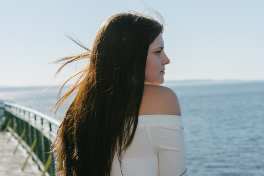 young woman leaning on ship railing looking out onto water