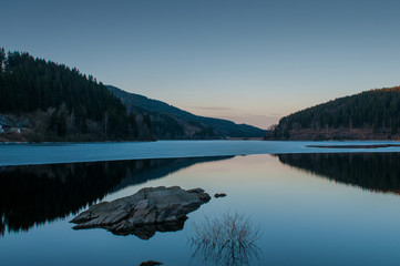 Beautiful twilight reflection in a mountain lake panorama, Oker dam in National Park Harz in Northern Germany