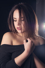 Naklejka premium Portrait of a beautiful young sexy brunette girl on a black background.