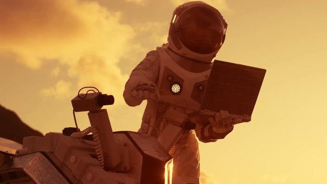 Astronaut in the Space Suit Works on Laptop, Adjusting Rover For Mars further Mars Exploration.Space Exploration Concept.First Manned Mission on Red Planet. Shot on RED EPIC-W 8K Helium Cinema Camera.