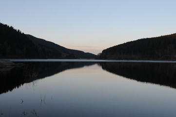 Fototapeta na wymiar Beautiful twilight reflection in a mountain lake panorama, Oker dam in National Park Harz in Northern Germany