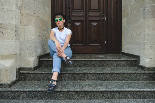 Beautiful young hipster woman posing sitting on stairs