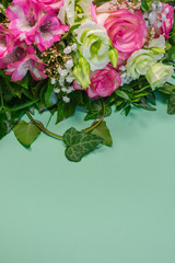 Close up view of a bunch or a bouquet of pink roses, pink Alstroemeria and white Lisianthus flowers  on green background with copy space