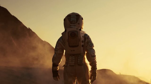 Following Shot of Astronaut Confidently Walking on Mars. Red Planet Covered in Gas and Smoke. Humans Overcoming Difficulties. Big Moment for the Human Race. Shot on RED EPIC-W 8K Helium Cinema Camera.