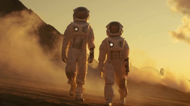 Two Astronauts in Space Suits Confidently Walking on Mars, Exploration Expedition on the Planet's Surface. Red Planet Covered in Rocks, Gas and Smoke. Humans Overcoming Difficulties. 