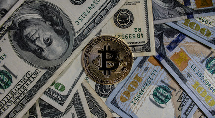 Bitcoin cryptocurrency on top of 100 dollar bills 