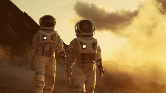 Two Astronauts in Space Suits Confidently Walking on Mars, Exploration Expedition on the Planet's Surface. Red Planet Covered in Rocks, Gas and Smoke.