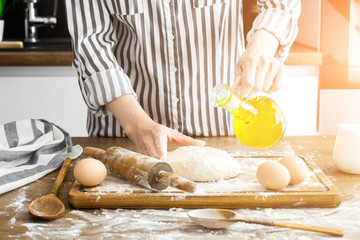 Female hands making dough on kitchen background