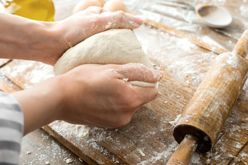 Female hands making dough on kitchen background