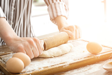 Female hands making dough on kitchen background