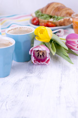 Two glasses of espresso. Easter breakfast. Fresh tulips of pink color and eggs of different colors