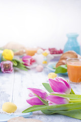 Easter breakfast of croissants and coffee, natural juice. Fresh spring tuips of pink color. White wooden table. Free space for text