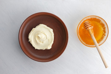 Sour cream, cottage cheese, dairy product in a clay bowl, cottage cheese on a white background in rustic style, honey and wooden stick, cream in a brown plate, French breakfast, copy space, minimalism