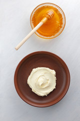 Sour cream, cottage cheese, dairy product in a clay bowl, cottage cheese on a white background in rustic style, honey and wooden stick, cream in a brown plate, French breakfast, copy space, minimalism