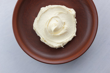 Sour cream, cottage cheese, dairy product in a clay bowl, cottage cheese on a white background in rustic style, honey and wooden stick, cream in a brown plate, French breakfast, copy space, minimalism