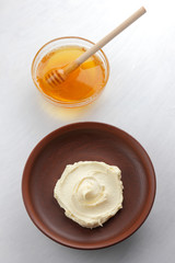 Sour cream, cottage cheese, dairy product in a clay bowl, cottage cheese on a white background in rustic style, honey and wooden stick, cream in a brown plate, French breakfast, copy space, minimalism