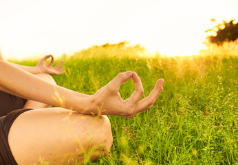 Woman's hand meditating in a field at sunset. Peaceful meditation concept.