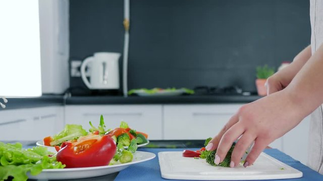 healthy food, hands slicing fresh green broccoli for salad on a cutting board at kitchen