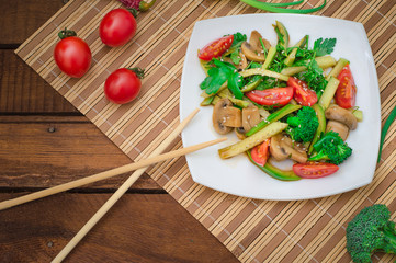 Salad with mushrooms, avocado, tomatoes and greens. Wooden rustic background. Top view
