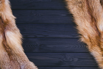 Red fox skin on a black wooden background. Beautiful fur of a red fox