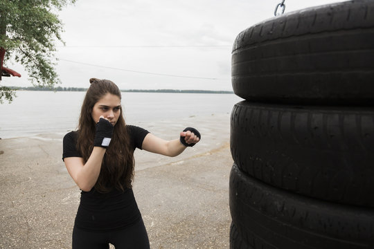Woman boxer punching tires outdoors
