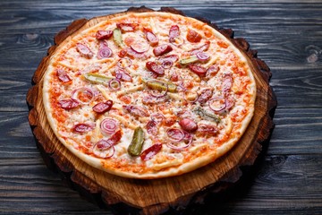 Appetizing pizza with salami, onions and gherkins, close up. Italian food, restaurant menu