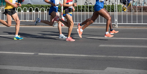 Fototapeta premium Legs of marathon runners running on city road