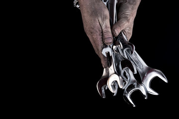 Man's hand holds steel wrenches on black background. Concept car service. Free space for text.