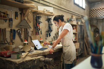 Furniture designer at the workshop working on a tablet