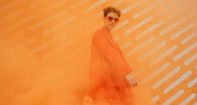 Young woman with orange clothes surrounded by orange smoke