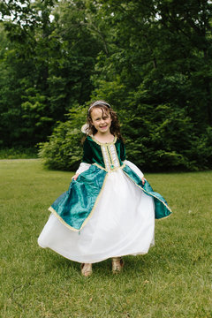 little girl wearing a princess dress and smiling outside in a park
