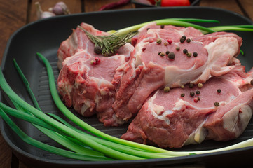 Ingredients for cooking rib eye roast beef steak on black iron grilling pan. Wooden rustic background. Top view, horizontal composition