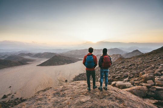 Hiking couple on a mountain summit watching the sunset over a desert wilderness