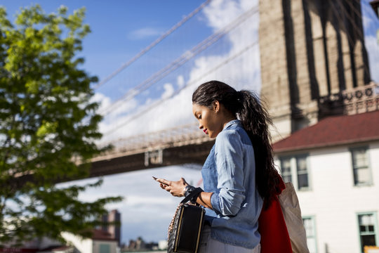 Woman using mobile phone outdoor.Brooklyn, New York.