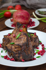 Steak on ribs, cooked on a grill with pomegranate on a white plate. Wooden rustic background. Top view