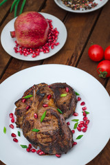 Steak on ribs, cooked on a grill with pomegranate on a white plate. Wooden rustic background. Top view