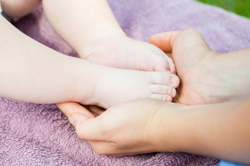 Baby feet in mother hands. Tiny newborn baby feet, concept of happy family. Fake color tone of photo..