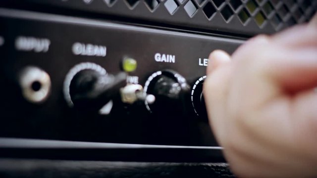 The guy increases and decreases the volume on the power amplifier.