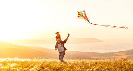 happy family father and child daughter run with  kite on meadow.